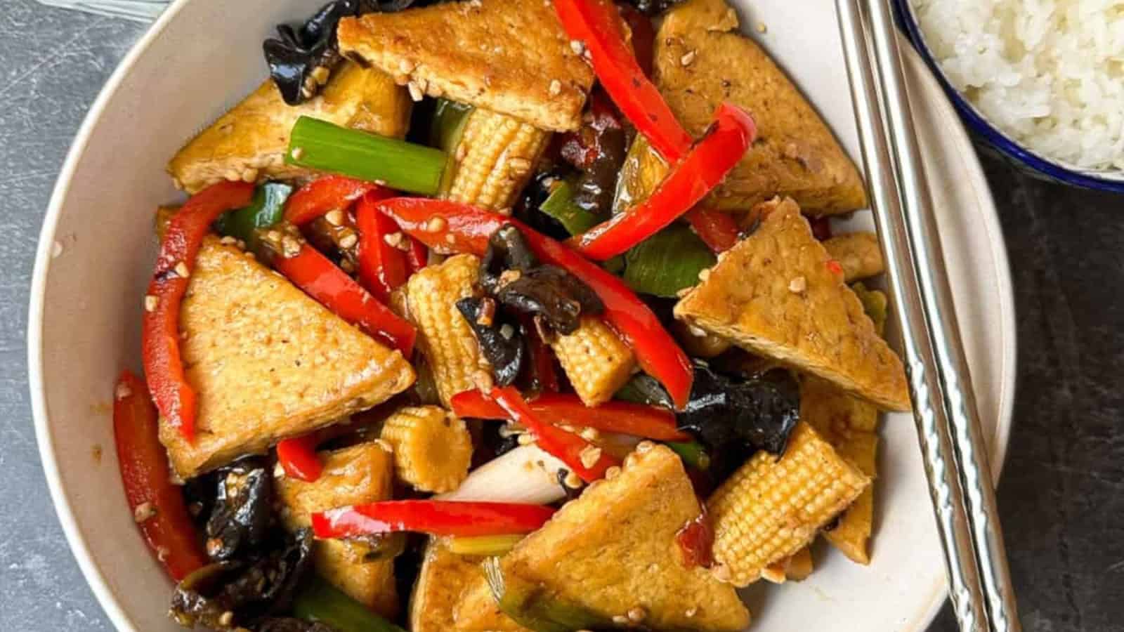Spicy and savory Hunan-style tofu stir-fry on a plate with a pair of silver chopsticks.