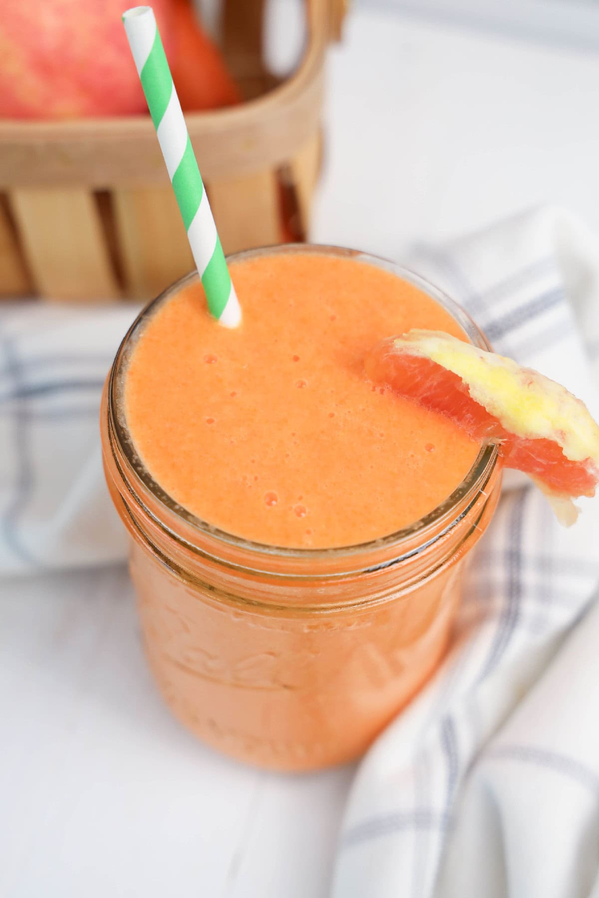 A smoothie with a straw and a slice of orange.