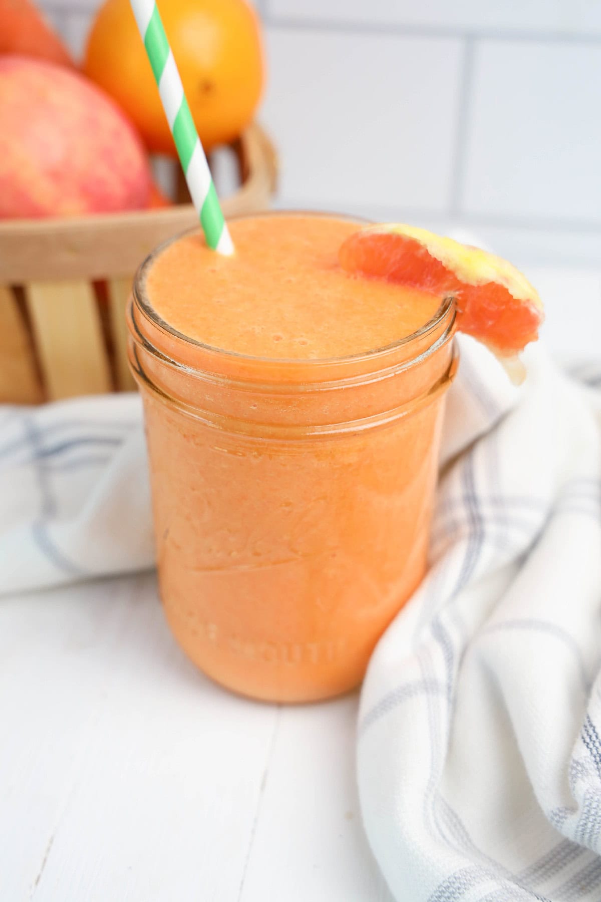 A smoothie with orange slices and a straw.