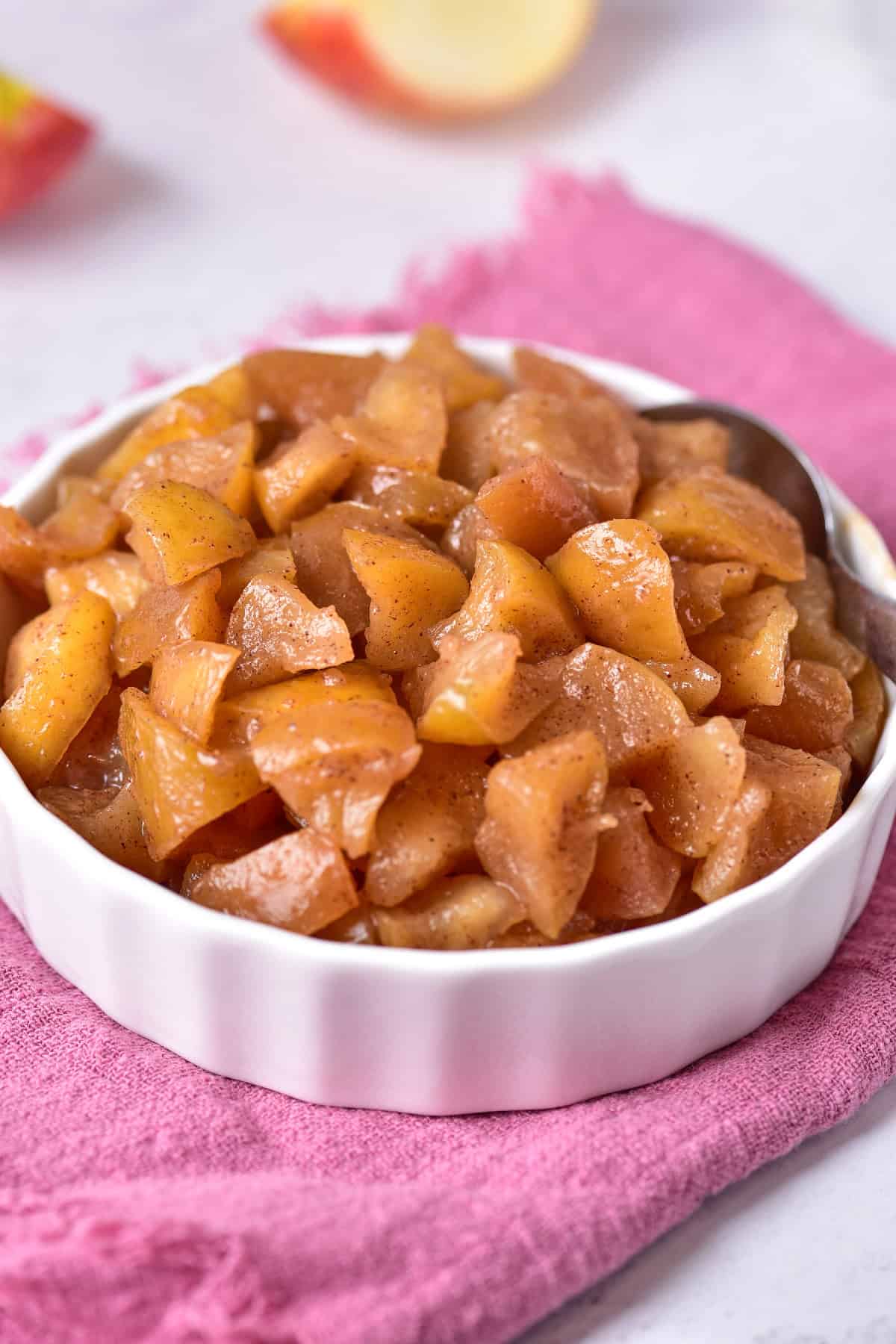 Cooked apples in a bowl, resting on a cozy pink towel.