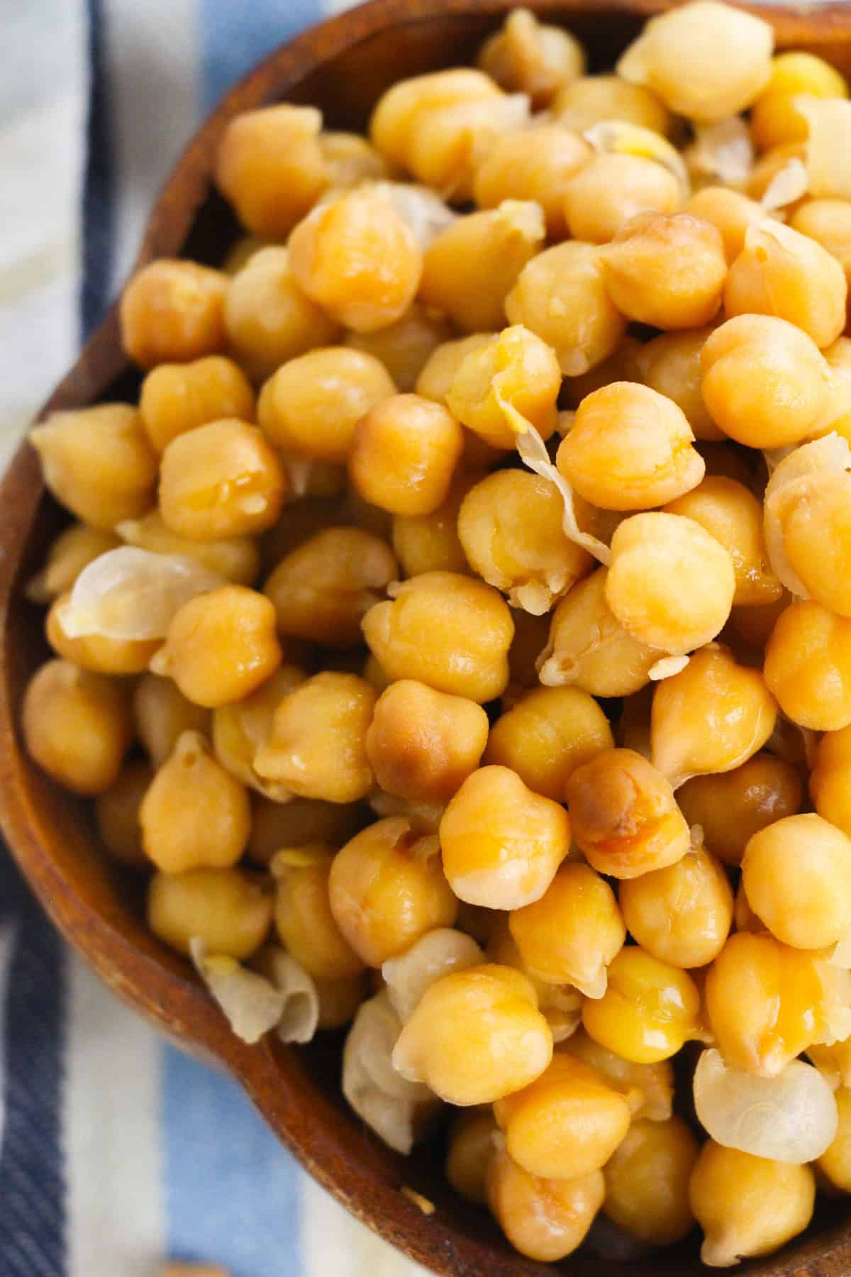Close-up view of perfectly cooked chickpeas in a wooden bowl.