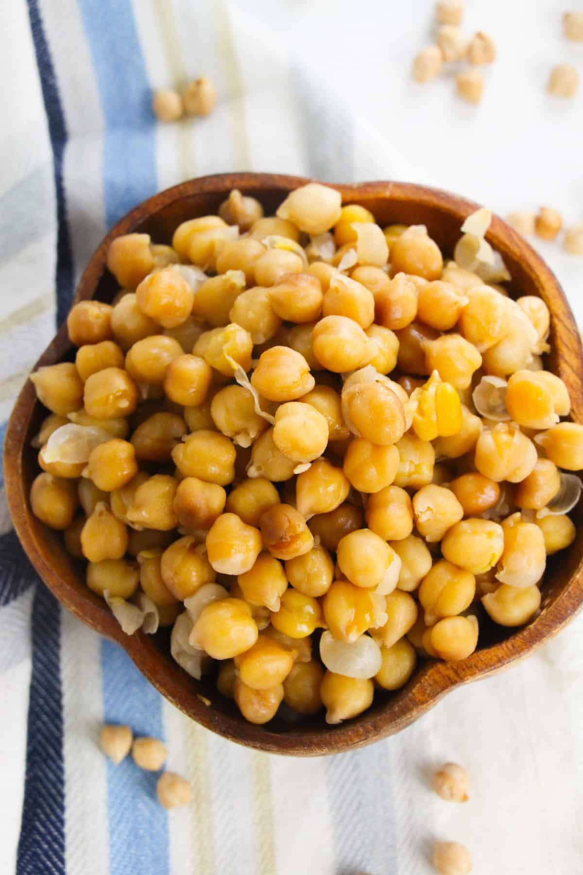 Close-up of cooked chickpeas in a brown wooden bowl.