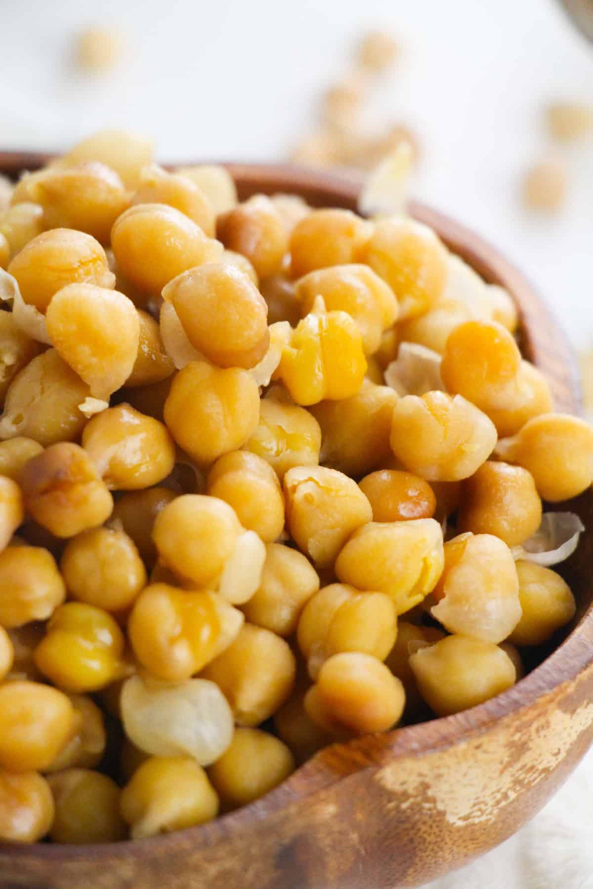 Close-up of perfectly cooked chickpeas in a wooden bowl.