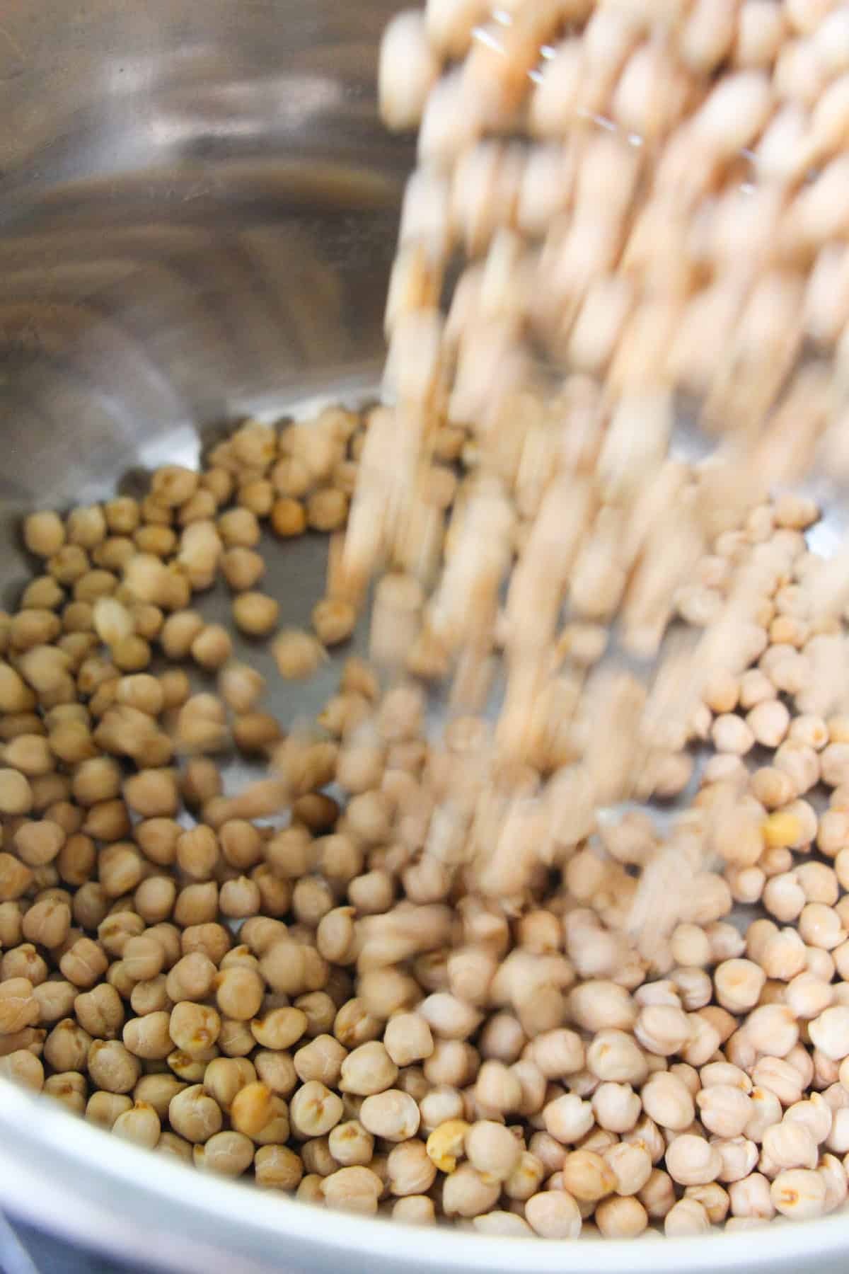 Pouring dried chickpeas into the inner pot of an Instant Pot pressure cooker.