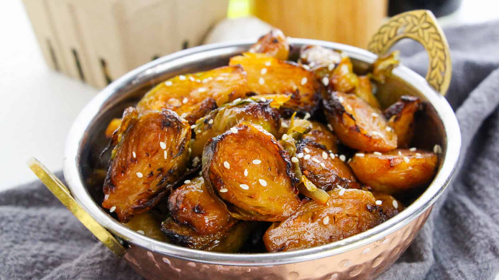 Close-up view of Brussels sprouts coated in gochujang glaze and sprinkled with sesame seeds.