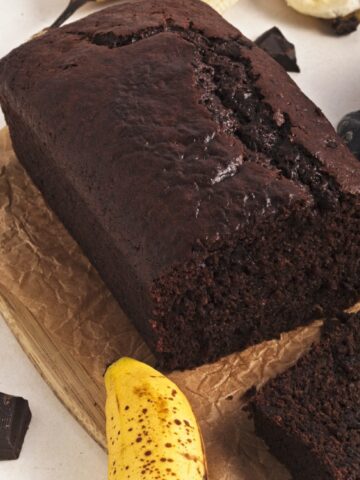 Square cropped image of vegan chocolate banana bread loaf with banana and chocolate pieces.