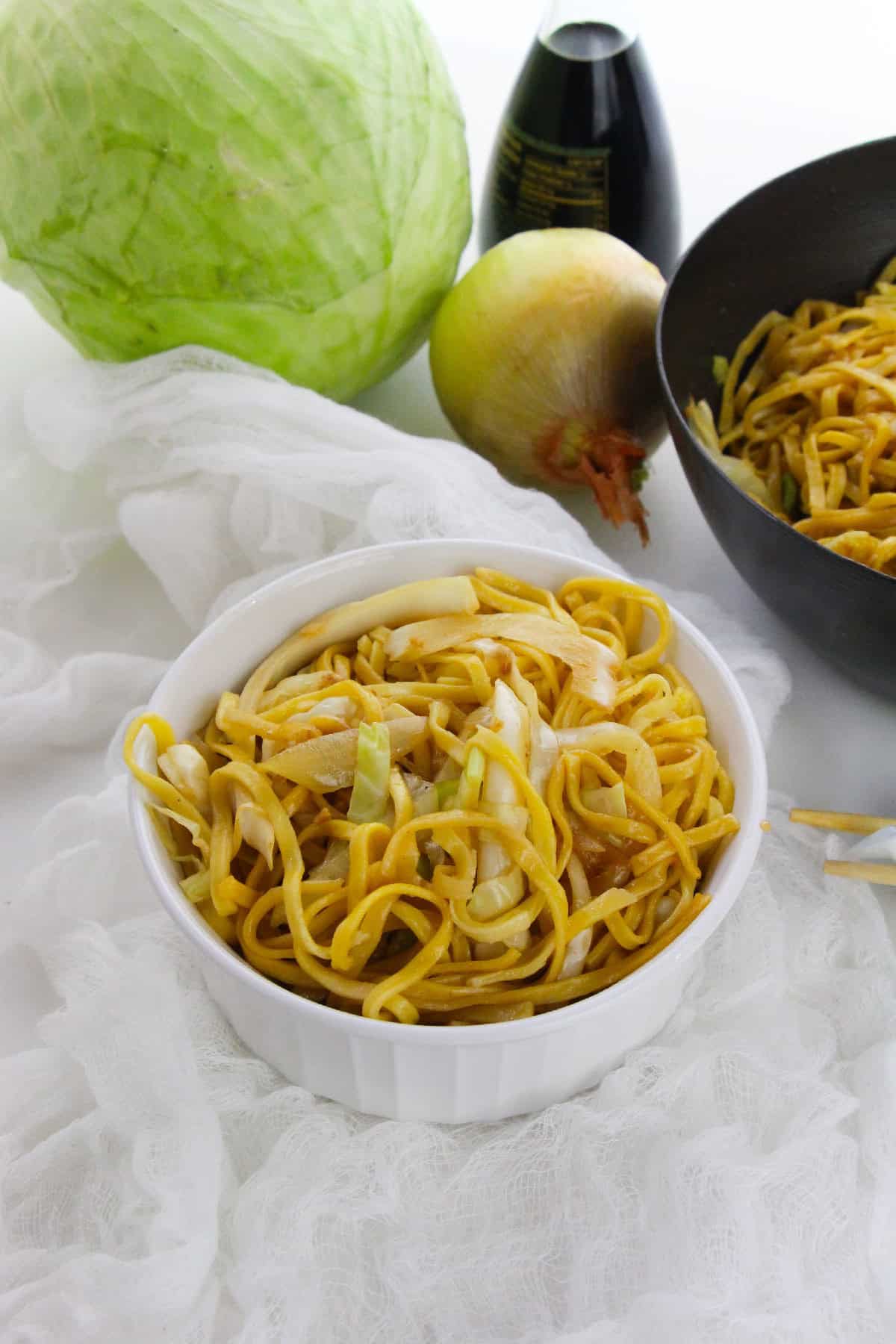 Simple vegetarian chow mein with golden noodles and cabbage slices.