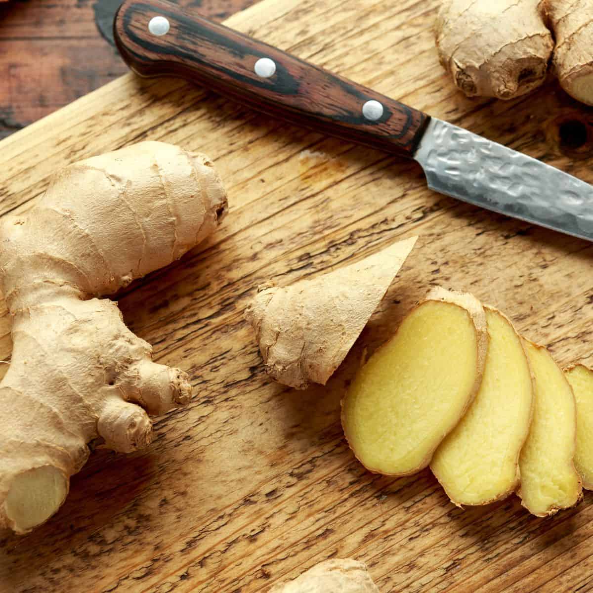 Sliced ginger pieces arranged on a wooden board.