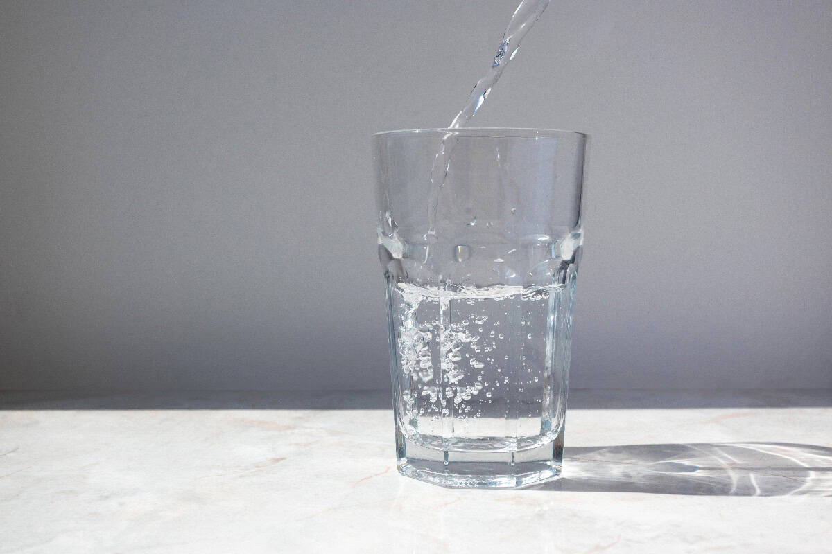 A clear glass being filled with water on a bright surface, showing hydration and healthy lifestyle habits.