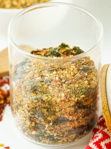 Close-up jar filled with homemade Japanese 7 spice blend, showing sesame seeds, seaweed, red pepper flakes, and aromatic seasonings on a bright kitchen surface.