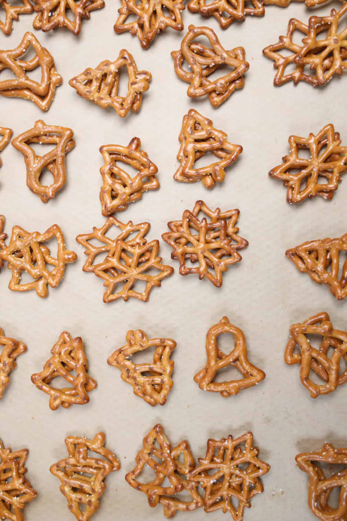 Christmas-shaped pretzels arranged on a parchment-lined baking sheet.