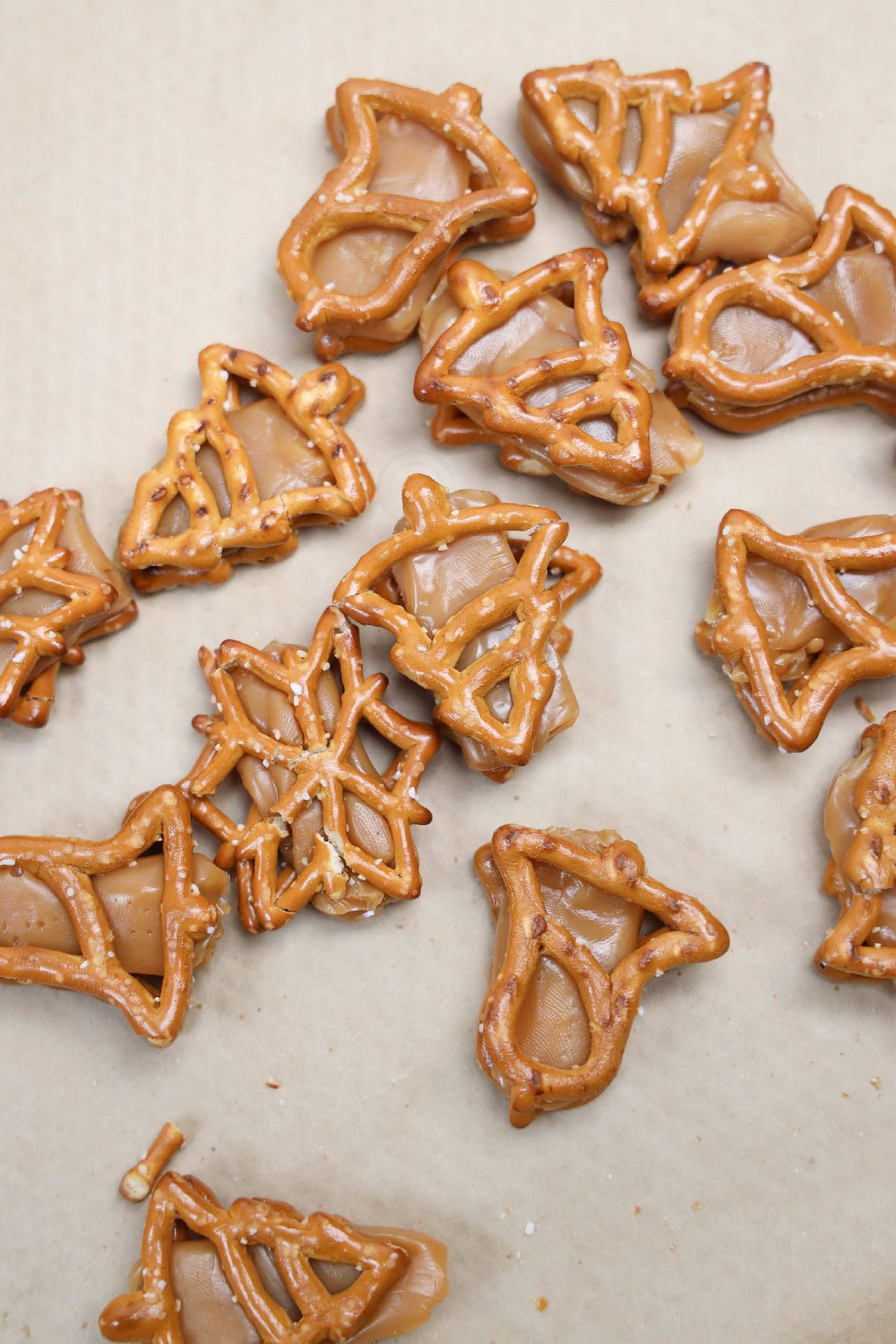 Holiday pretzels filled with soft caramel pieces on a baking sheet.