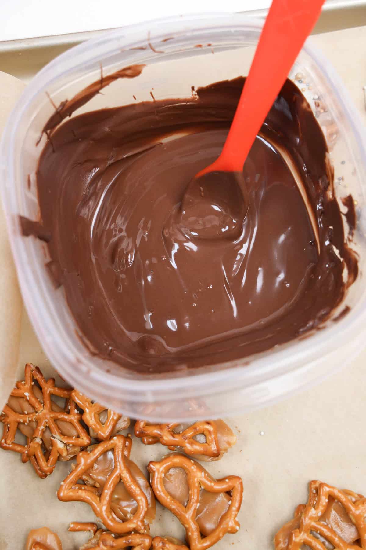 Container of melted milk chocolate with pretzels ready to be dipped.
