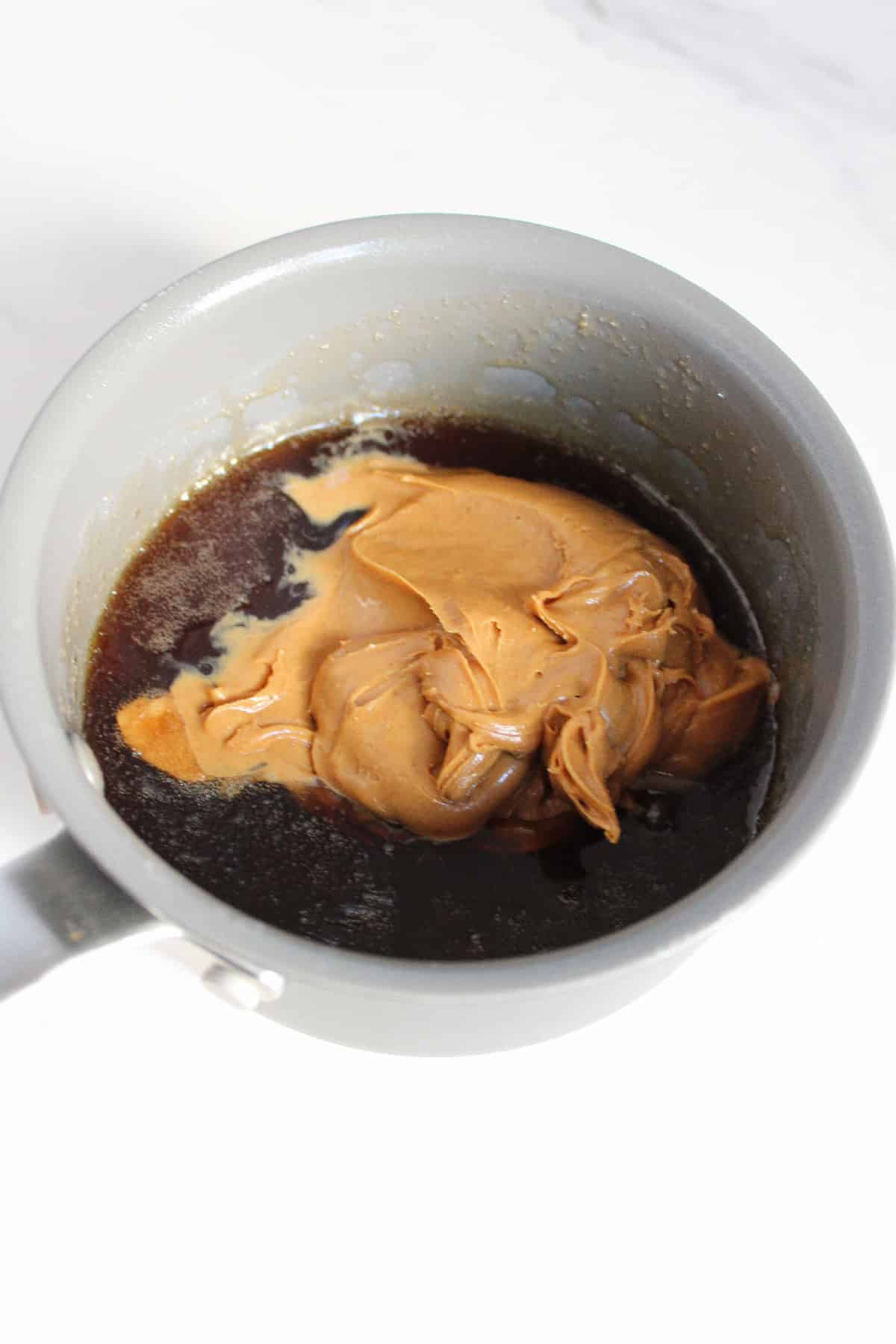 Peanut butter added into the melted sugar mixture in a saucepan.