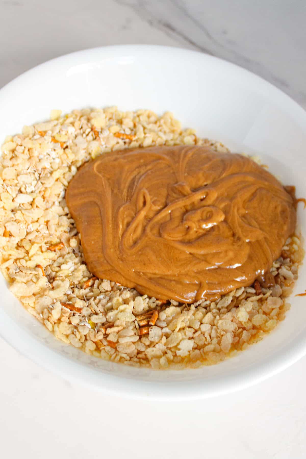 Warm peanut butter mixture poured over the dry cereal, pretzels, and oats.