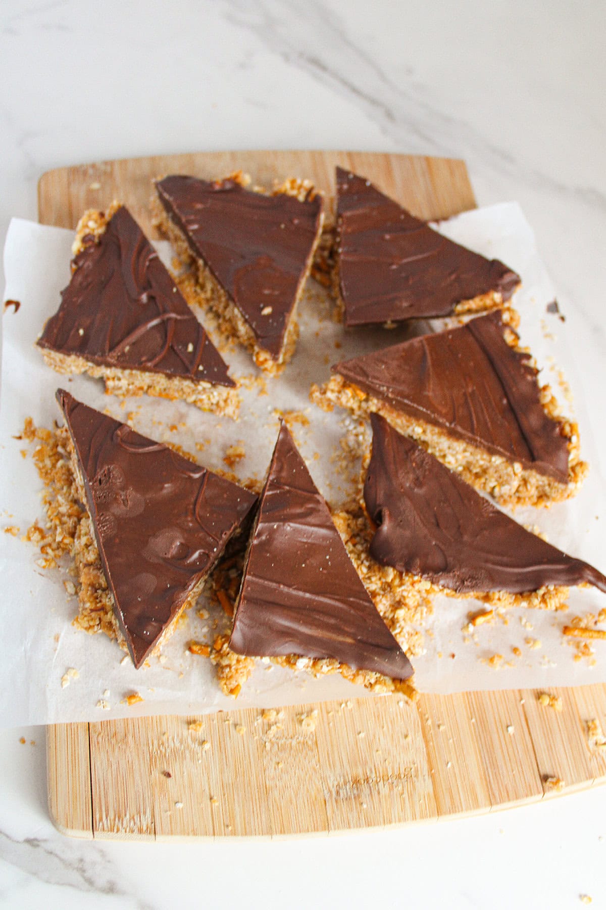 Triangular chocolate topped bars cut into Christmas tree shapes on parchment.