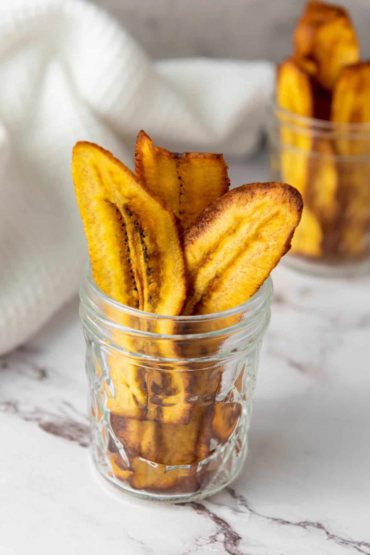 Crunchy chifles plantain chips arranged upright on a marble surface.