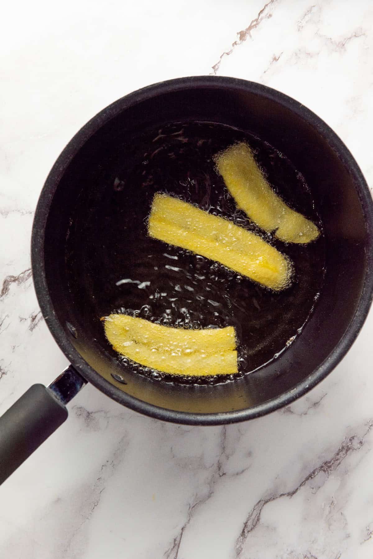 Homemade chifles frying until golden and crisp.
