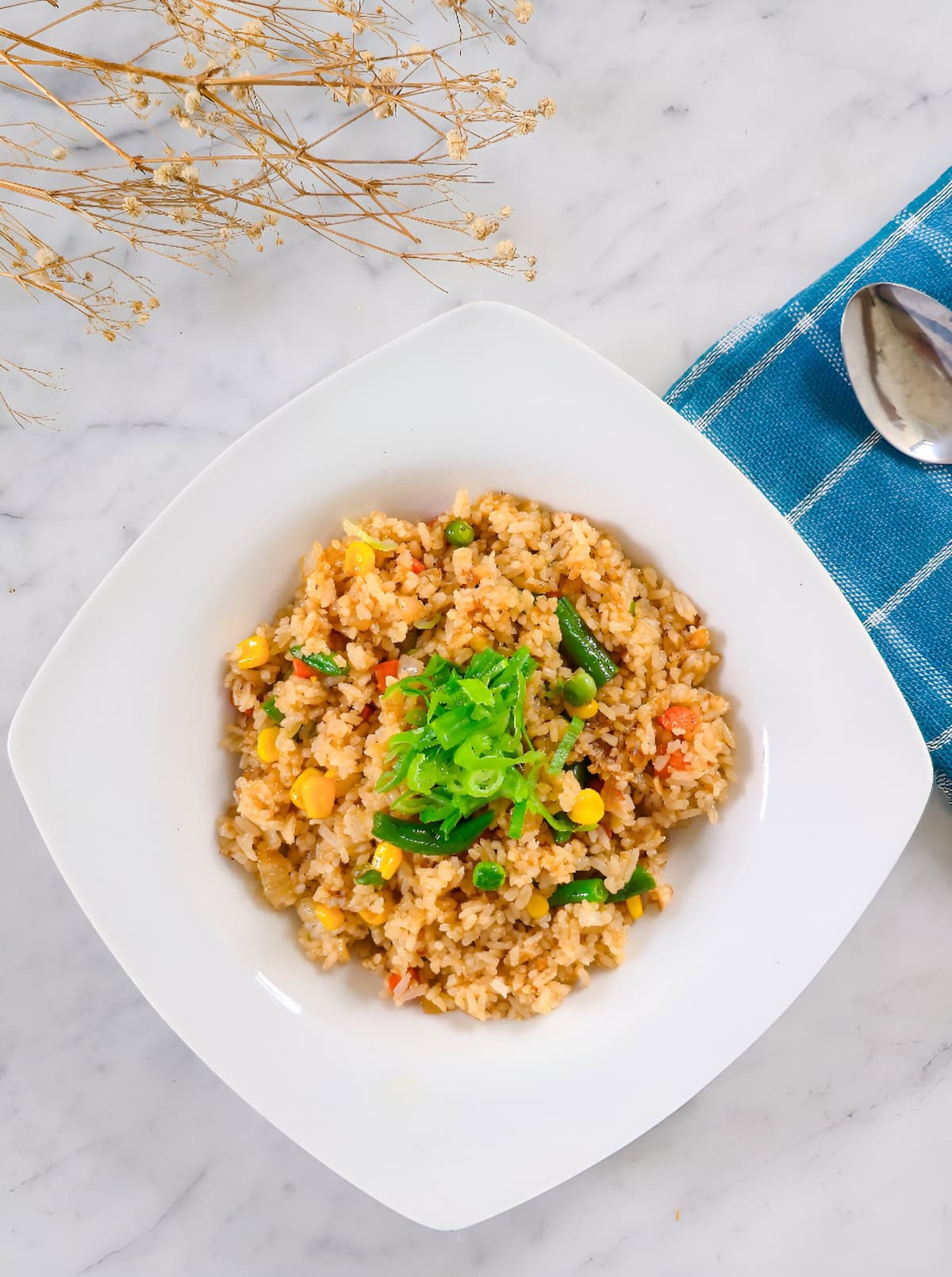 Frozen vegetable fried rice served in a white bowl and garnished with sliced green onions.