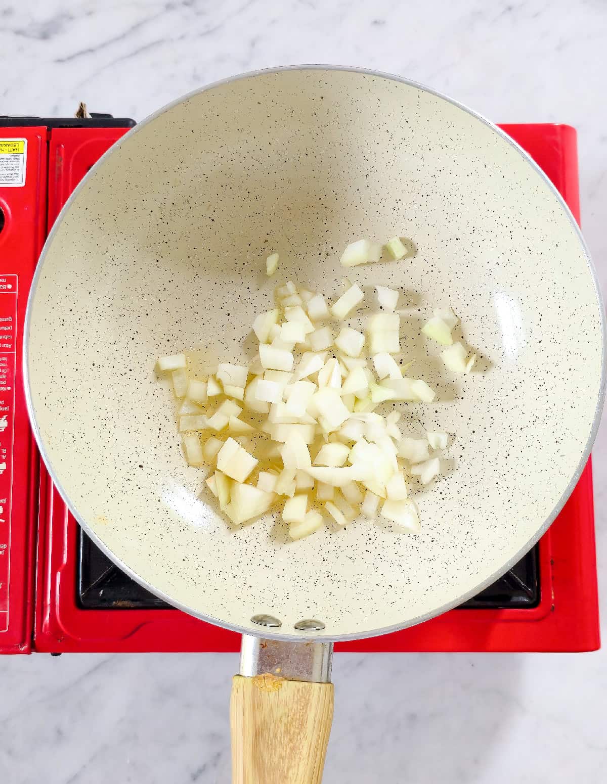 Diced onions saut&eacute;ing in a pan with oil to start vegetable fried rice.