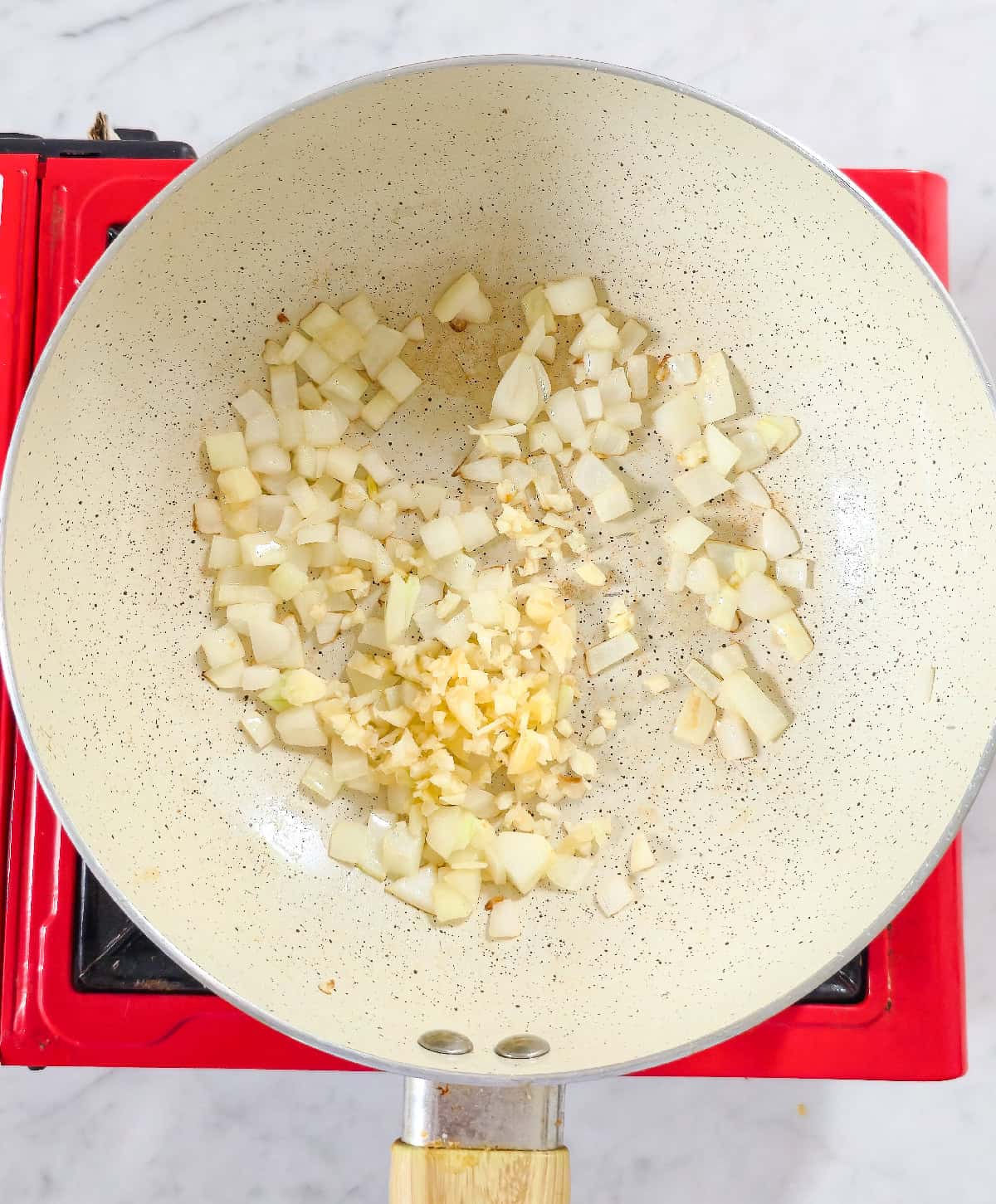 Saut&eacute;ed onions with freshly minced garlic cooking in a pan.