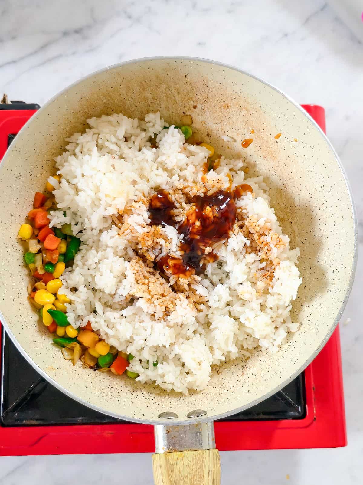 Sauce mixed into rice and vegetables while cooking fried rice.