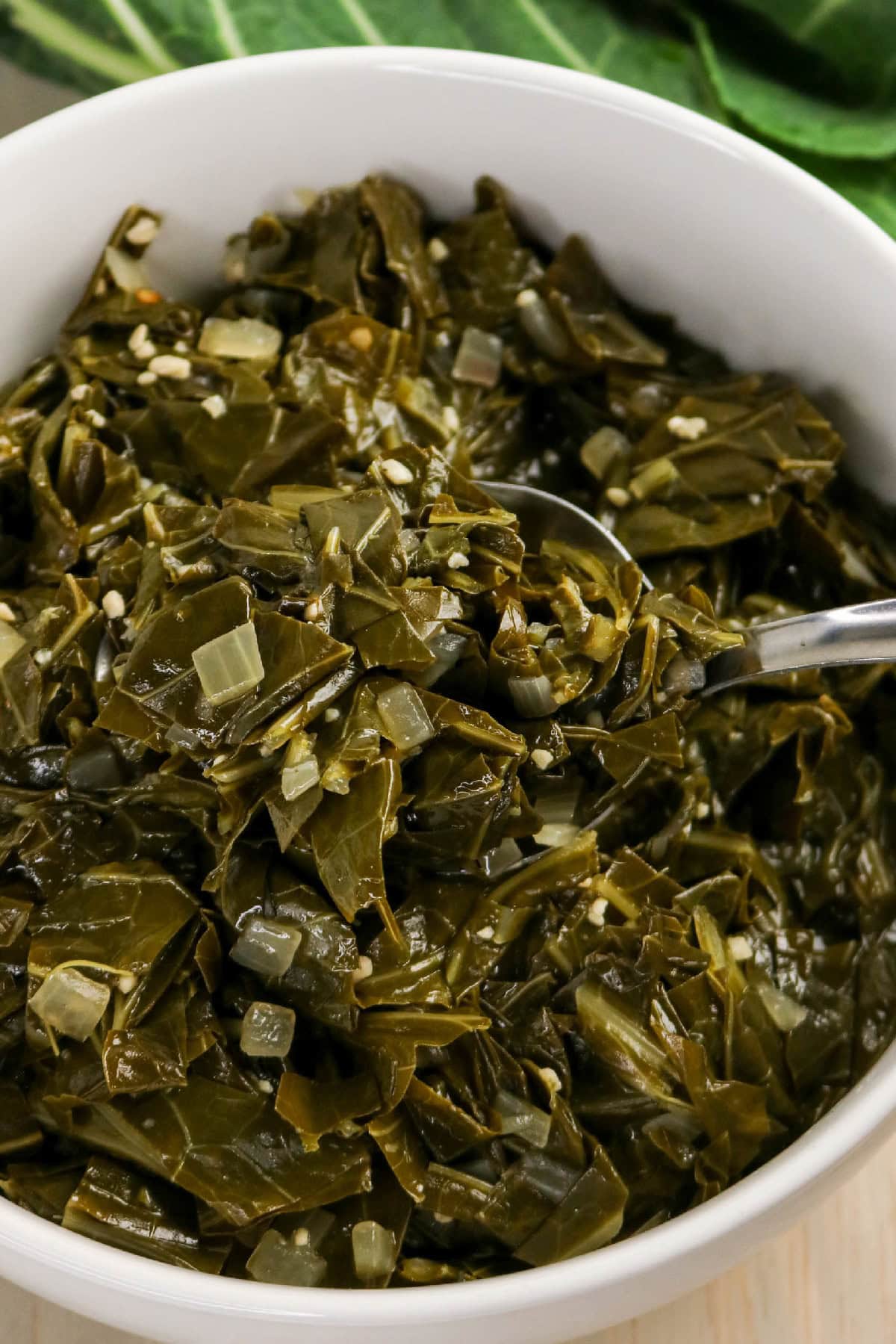 Close-up of braised collard greens with tender leaves and diced onions.