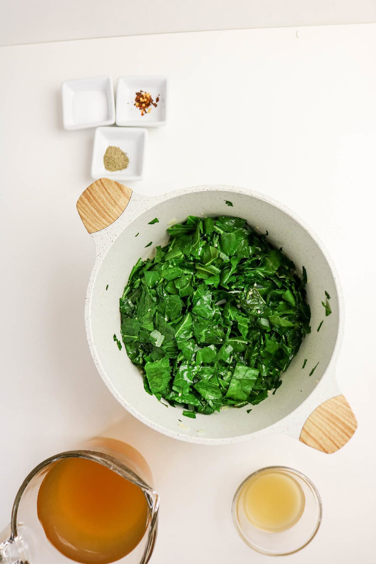 Collard greens beginning to wilt as they cook down.
