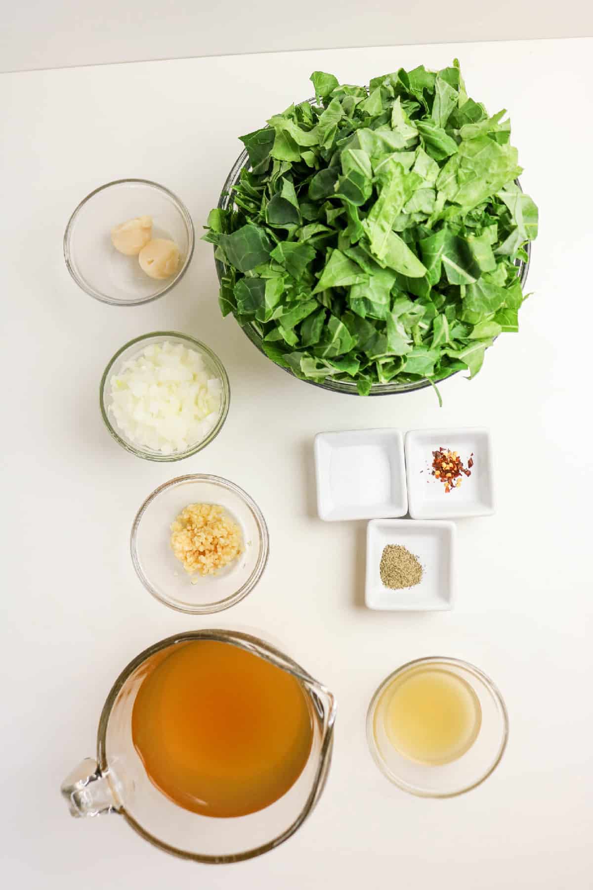 Braised collard greens ingredients arranged on a white surface.