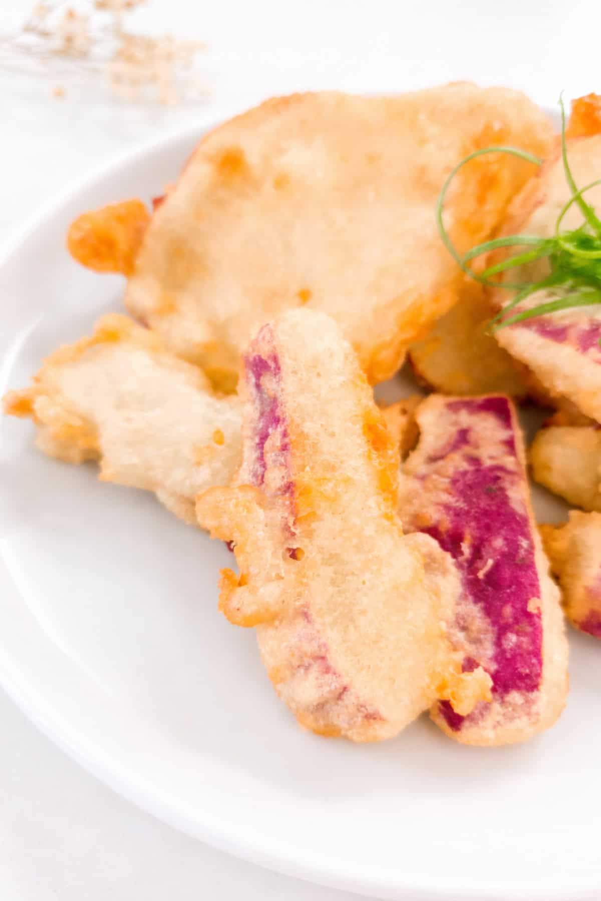Close-up of crispy sweet potato tempura showing golden batter and purple sweet potato interior.