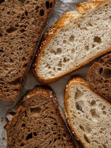 Light and dark artisan bread slices laid out on textured parchment paper.