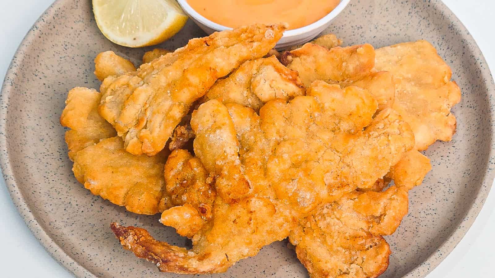 Air fryer oyster mushrooms served with lemon wedges and creamy dipping sauce on a gray plate.
