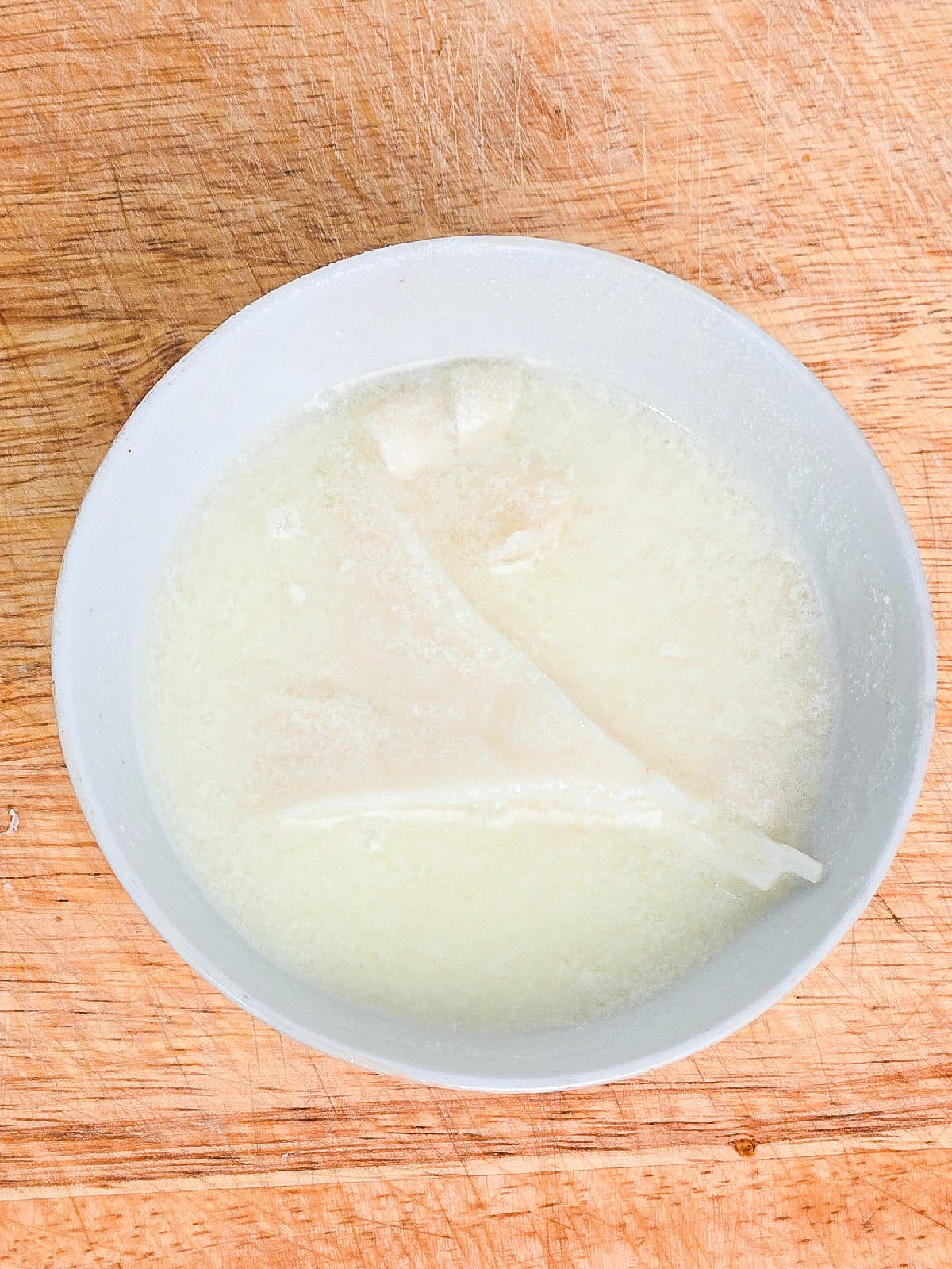 Oyster mushrooms soaking in a light batter mixture before coating.