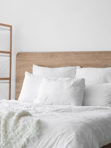 Simple bedroom design with a wood bed frame, crisp white bedding, and muted neutral tones.