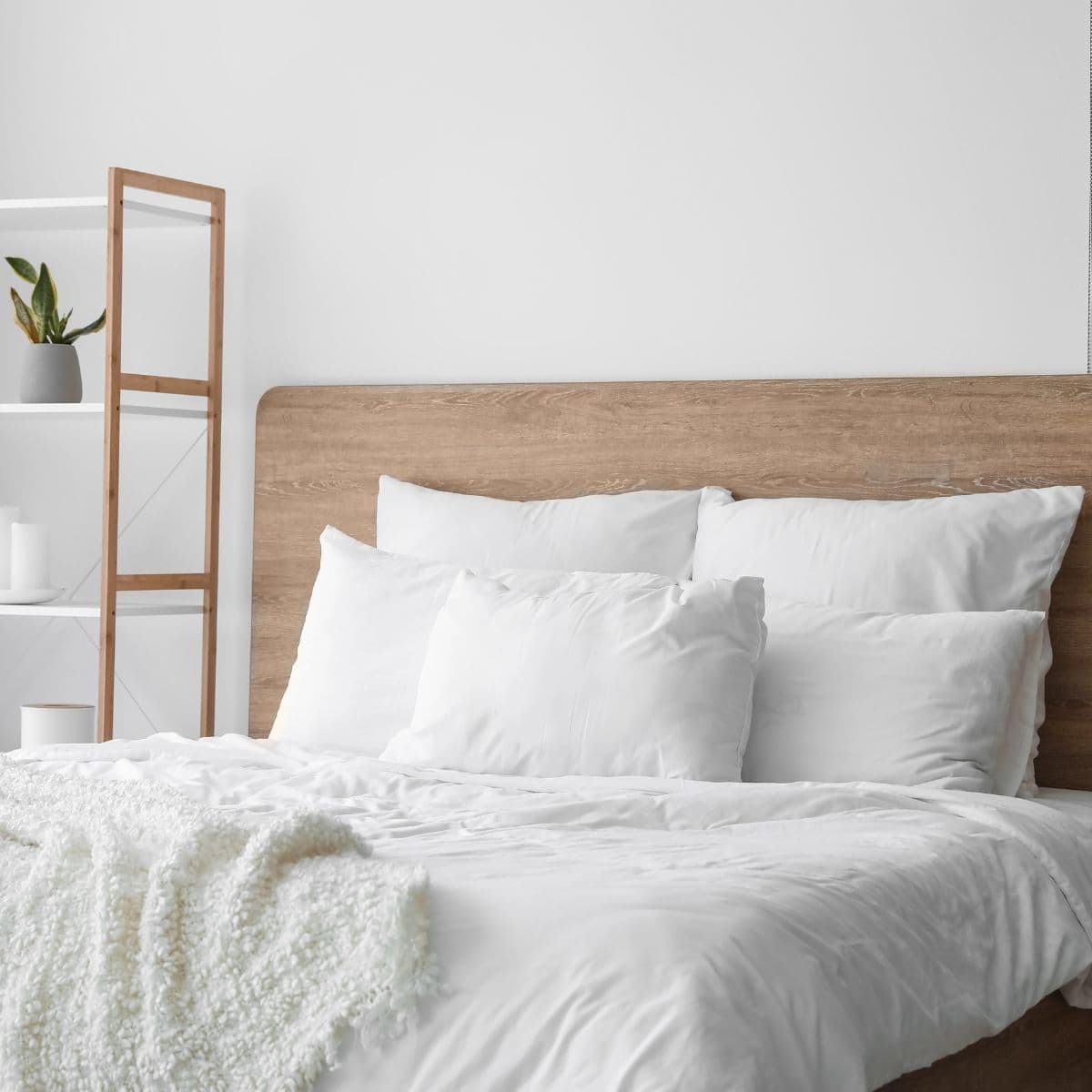 Simple bedroom design with a wood bed frame, crisp white bedding, and muted neutral tones.
