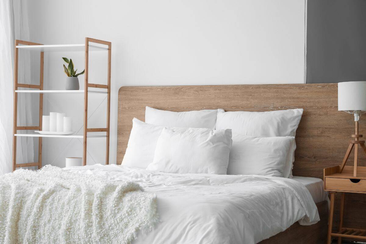 Minimalist bedroom with a wooden bed frame, white bedding, and neutral decor.