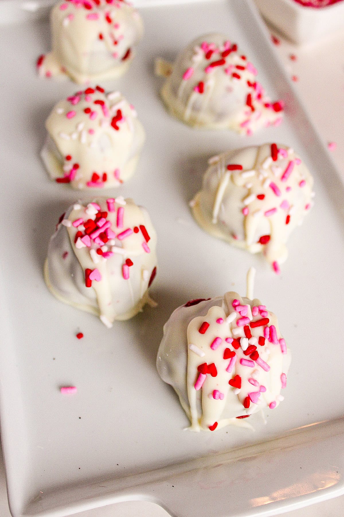 Overhead view of white chocolate red velvet truffles on a white plate.