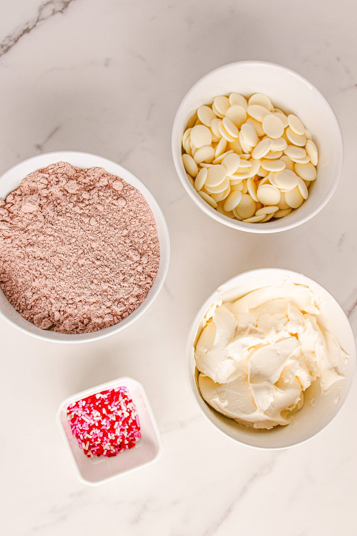 Red velvet truffle ingredients including cake mix crumbs, cream cheese, white chocolate melts, and festive sprinkles.