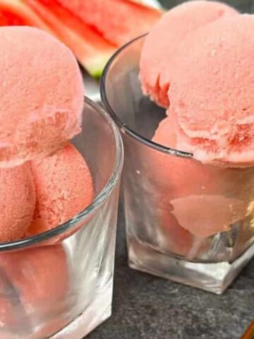 Two serving of watermelon ice cream in cups.