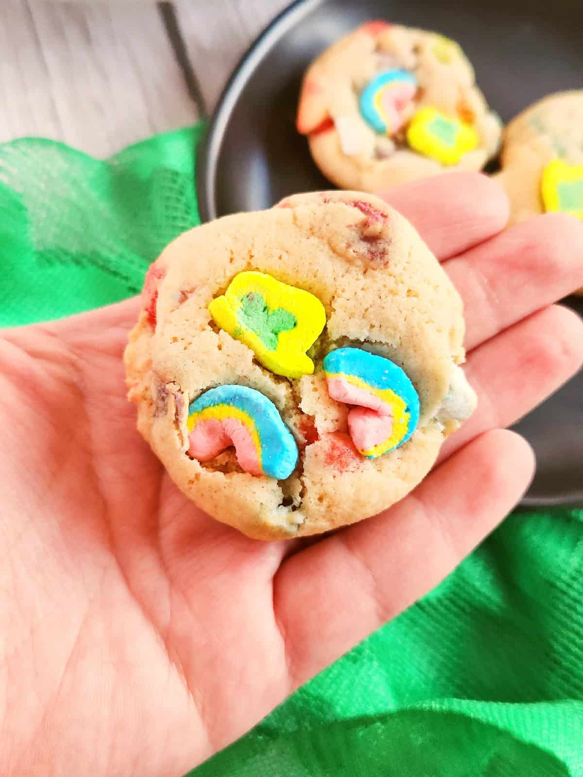 Side view of Lucky Charms cookies on a black plate with green cloth background.