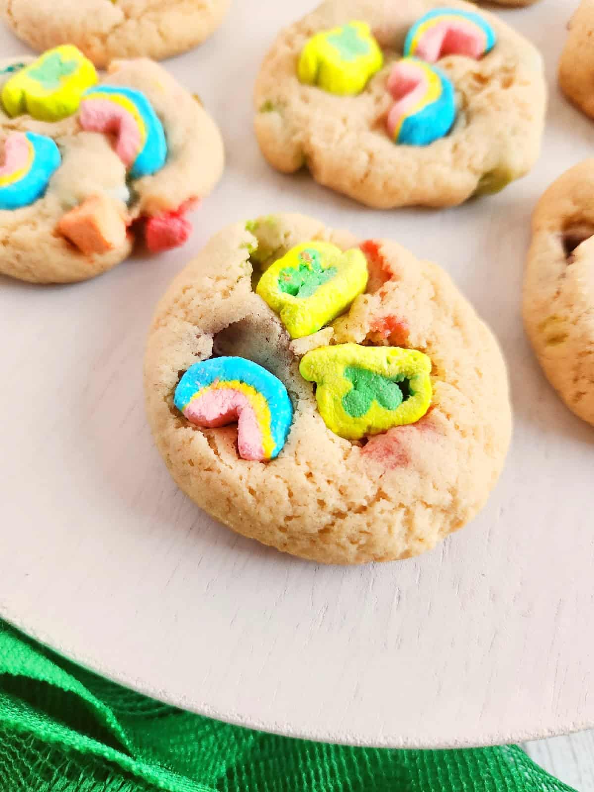 Fresh baked Lucky Charms cookies arranged on a white serving plate.