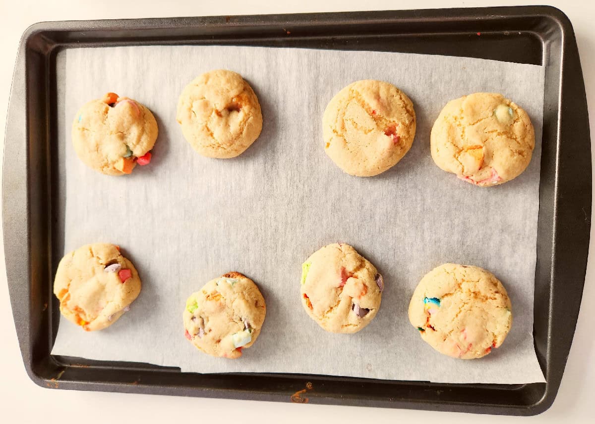 Freshly baked Lucky Charms cookies cooling on a baking sheet.