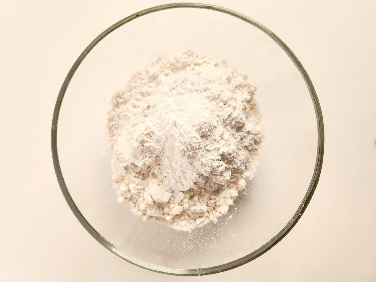 All-purpose flour and baking powder measured in a bowl for cookie dough.