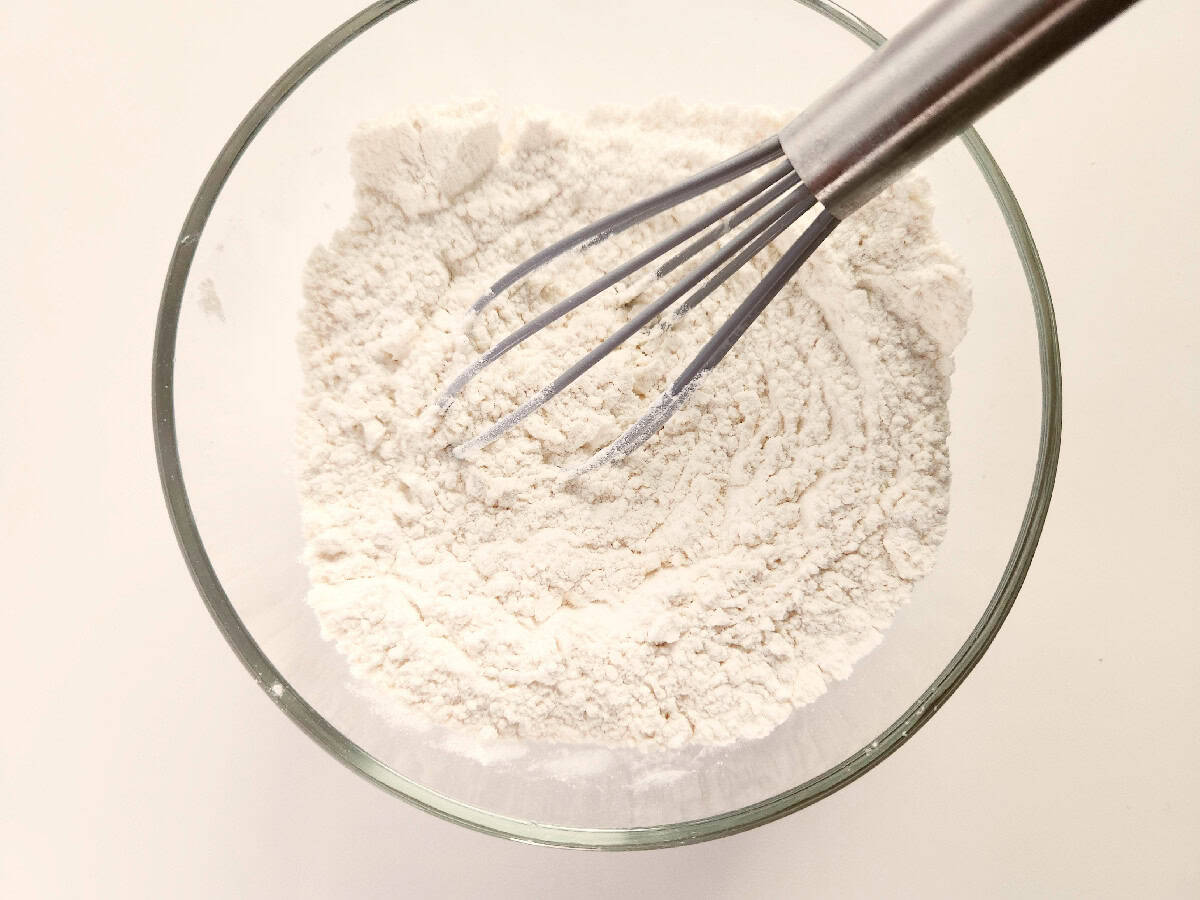 Dry ingredients being whisked together in a glass bowl.