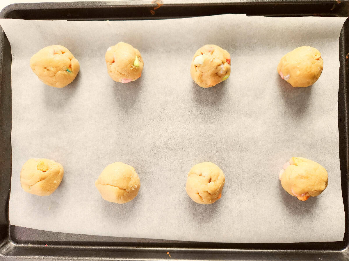 Cookie dough rolled into balls and placed on a parchment-lined baking sheet.
