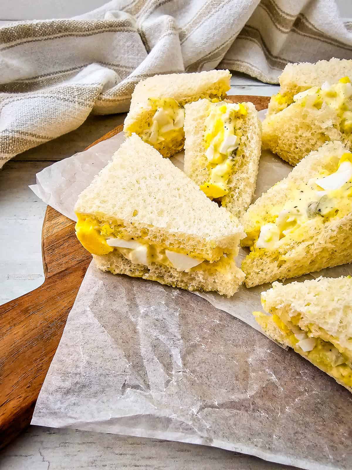 Side view of egg salad tea sandwich showing fluffy bread and rich, creamy egg filling inside.