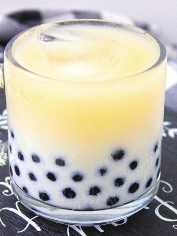 Black tea boba milk tea in a glass mug with tapioca pearls.