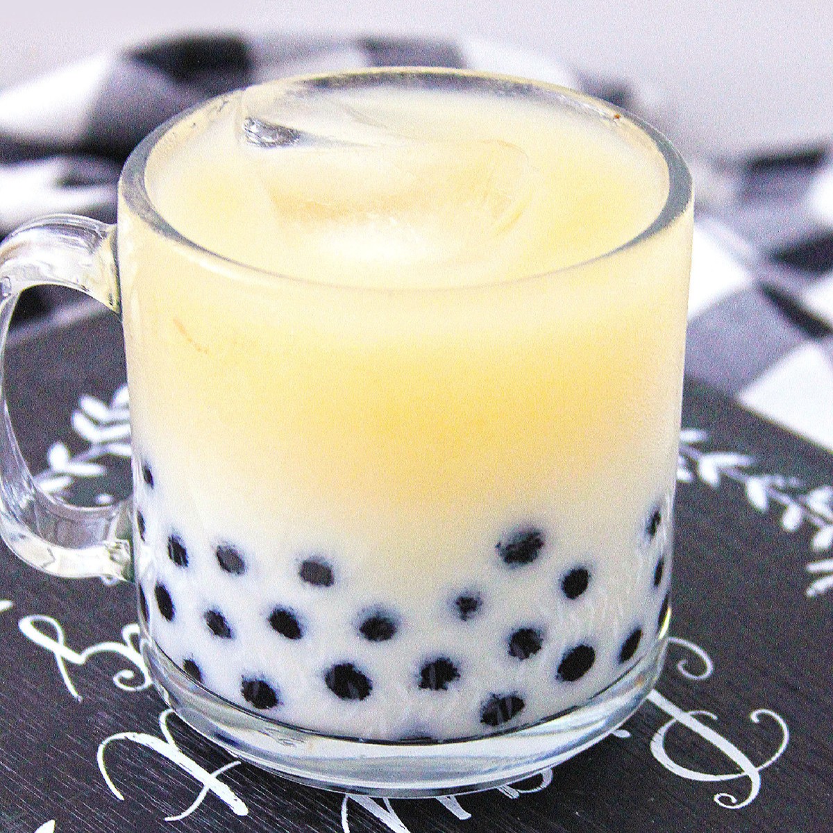 Black tea boba milk tea in a glass mug with tapioca pearls.