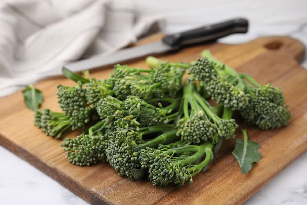 Broccolini on a wooden cutting board, showing its tender stems and small buds.