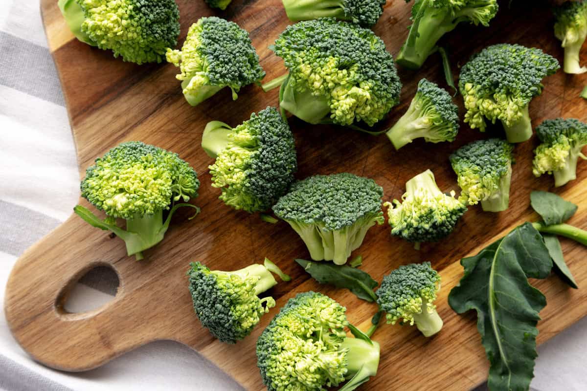 Chopped broccoli florets on a wooden board, ready for cooking or meal prep.